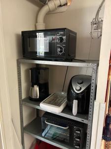 a microwave and a coffee maker on a shelf at Genbrugsfabrikkens Tiny apartment in Holbæk