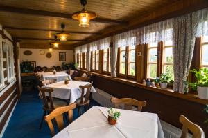 a restaurant with tables and chairs and windows at Pension Skalicky in Pec pod Sněžkou