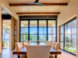 a dining room with a table and chairs and large windows at Tombolo Bay in Dickwella