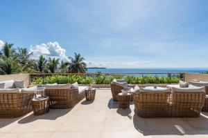 a patio with wicker chairs and the ocean in the background at Tombolo Bay in Dickwella