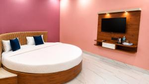 a bedroom with a bed and a flat screen tv at Hotel Asha Palace By Basotel in Deoghar