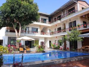 a hotel with a swimming pool in front of a building at Thach's Homestay Tam Coc in Vũ Lâm
