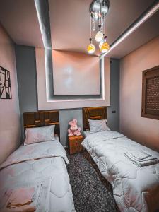 a room with two beds and a picture on the wall at Merzouga Desert Apartment in Merzouga