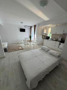 a white bedroom with a large bed and a table at Beside Gardens in Otopeni