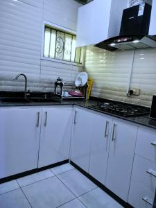 a kitchen with white cabinets and a sink at UG Apartment Lagos in Isagatedo