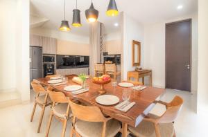 a dining room with a large wooden table and chairs at Tridi Beach Villa by Nagisa Bali in Tanah Lot