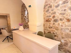 a kitchen with a stone wall and a counter with chairs at Opus Luxury Maisonette in Chios