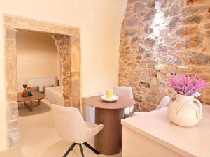 a room with a table and chairs and a stone wall at Opus Luxury Maisonette in Chios