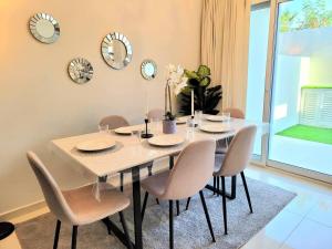 a dining room table with chairs and clocks on the wall at Damac Hills 2 Villa Pool Front + Waterpark Access in ‘Ūd al Bayḑāʼ