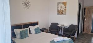 a bedroom with a bed with two chairs and a table at Villa Eliada in Tuzla