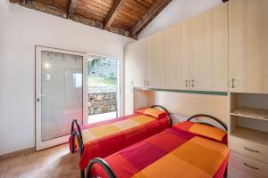 two beds in a room with a window at Tutti Frutti in Pompeiana