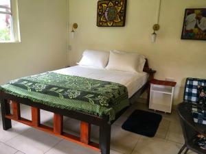a bedroom with a bed with a green blanket on it at Creole Cottage in Calibishie