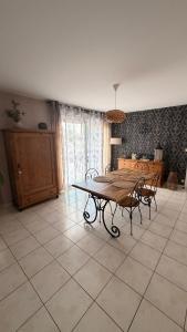a dining room with a table and chairs on a tile floor at Chez Delphine in Damery