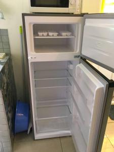 an empty refrigerator with its door open in a kitchen at Creole Cottage in Calibishie