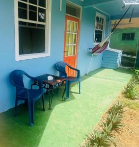 a house with two chairs and a table and an umbrella at Creole Cottage in Calibishie