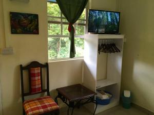 a room with a window and a table and a tv at Creole Cottage in Calibishie