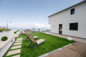 a backyard with a lawn and chairs and the ocean at Eva's house in São Vicente