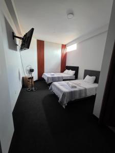 a hotel room with two beds and a fan at Javaz Hospedaje in Tarapoto