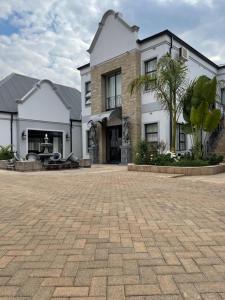a large white building with a palm tree in front of it at Ezulwini Villa hotel in Harare