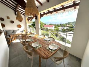 a dining room with a table and chairs and a balcony at Évasion Tropicale - vue et plage à 2 min in Les Trois-Îlets