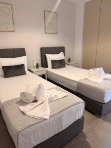two beds with towels on them in a room at City Vibes Corinth in Korinthos
