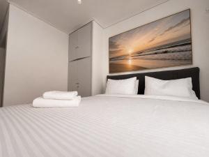 a bedroom with a large white bed with a painting on the wall at Oli' Studio in Oropos