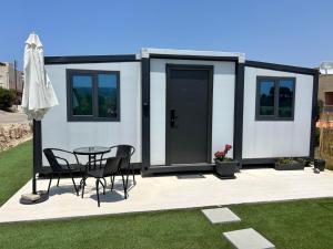 a tiny house with a table and chairs on a patio at Krisanto white in Prodhromi +3 photos