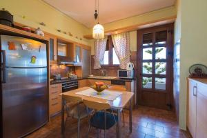 a kitchen with a table and a stainless steel refrigerator at Beachfront Family Villa Katerina with Private pool, Playground, BBQ & Amazing Sea Views! in Petres