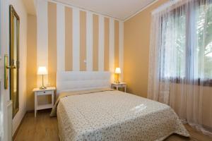 a bedroom with a bed and two tables and a window at Beachfront Family Villa Katerina with Private pool, Playground, BBQ & Amazing Sea Views! in Petres