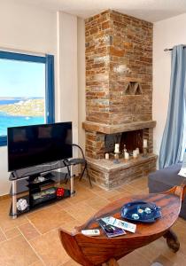 a living room with a tv and a brick fireplace at Andros Villa in Andros