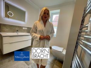 a woman standing in a bathroom with a sink at Fewo-meerblick-Rügen in Altefähr +30 photos