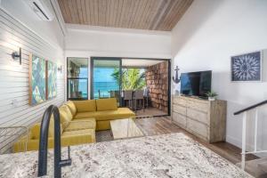 a living room with a yellow couch and a television at Modern-Rustic Beach Renovation Direct Oceanfront Penthouse in Kahana