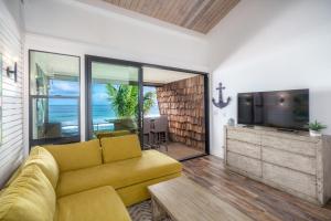 a living room with a yellow couch and a television at Modern-Rustic Beach Renovation Direct Oceanfront Penthouse in Kahana