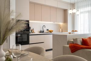 a kitchen with white cabinets and a living room at A&R Residence Nest in Arad