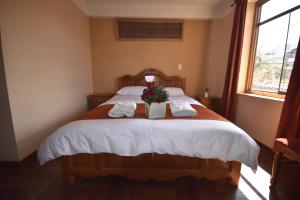 a bedroom with a bed with towels and flowers on it at Fuente de Agua in Cusco