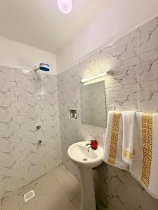 a white bathroom with a sink and a mirror at Escape Reef in Watamu