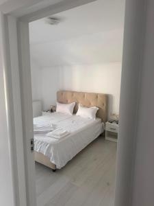 a bedroom with a bed with white sheets and pillows at AME Home Apartament 2 in Ocna-Mureşului