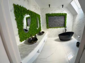 a bathroom with two sinks and a tub with ivy on the wall at AME Home Apartament 2 in Ocna-Mureşului