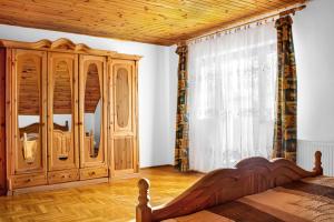 a bedroom with a wooden bed and a wooden cabinet at Wellez Vendégház in Sajóvelezd