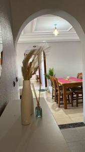 a dining room with a table and a vase with plants at charmant appartement forêt et mer in Tangier