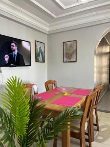 a dining room with a table and a tv on a wall at charmant appartement forêt et mer in Tangier