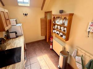 a kitchen with a refrigerator and a shelf with dishes at Meadow Cottage in Fowey