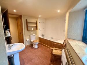 a bathroom with a toilet and a tub and a sink at Meadow Cottage in Fowey +16 photos