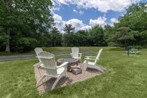 three white chairs and a table in the grass at Best Western Acadia Park Inn in Bar Harbor