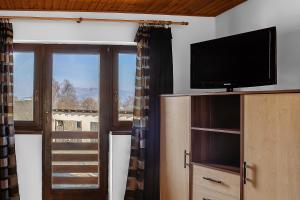 a living room with a flat screen tv and a window at Wellez Vendégház in Sajóvelezd