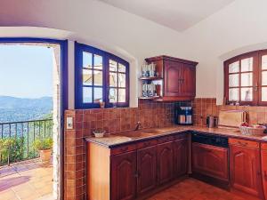 a kitchen with wooden cabinets and a balcony at Villa Balcon d'Azur by Interhome in Spéracèdes +21 photos