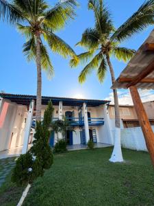 a view of the front of a house with palm trees at Santorini Suítes in Tamandaré