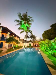 a swimming pool with a palm tree in front of a house at Santorini Suítes in Tamandaré