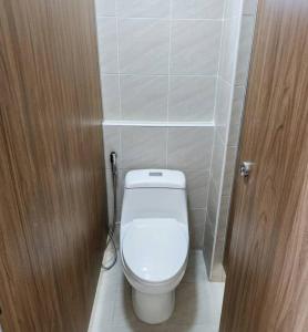 a bathroom with a white toilet and a wooden door at Hotel Backpack BTS ปุณณวิถี in Bangkok