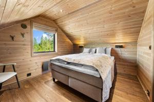a bedroom in a log cabin with a bed and a window at Reno Hytta in Eggedal